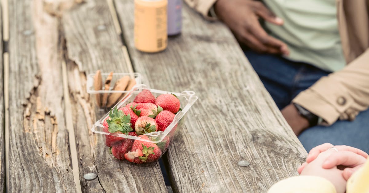 Can you identify this Serbian street food? - Crop anonymous couple sitting at shabby wooden table with strawberries and cookies near cans of soda while spending time in park Can you identify this Serbian street food? - Crop anonymous couple sitting at shabby wooden table with strawberries and cookies near cans of soda while spending time in park