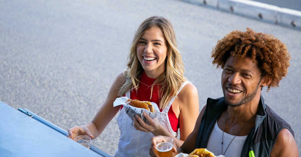 Can you make a sauce with beer? - Delighted multiethnic couple with drinks and food on street Can you make a sauce with beer? - Delighted multiethnic couple with drinks and food on street