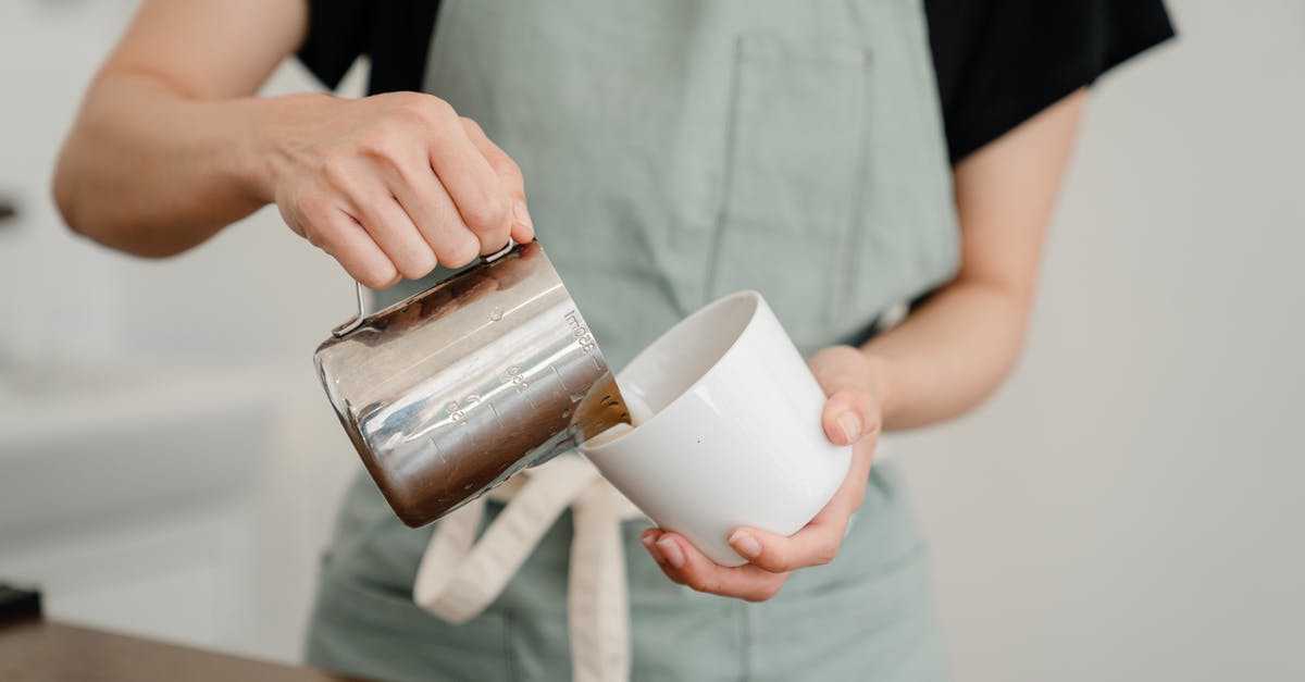 Can you make caramel with evaporated milk? - Crop unrecognizable barista in apron pouring milk from steel pitcher to white ceramic cup while preparing aromatic coffee in modern cafe