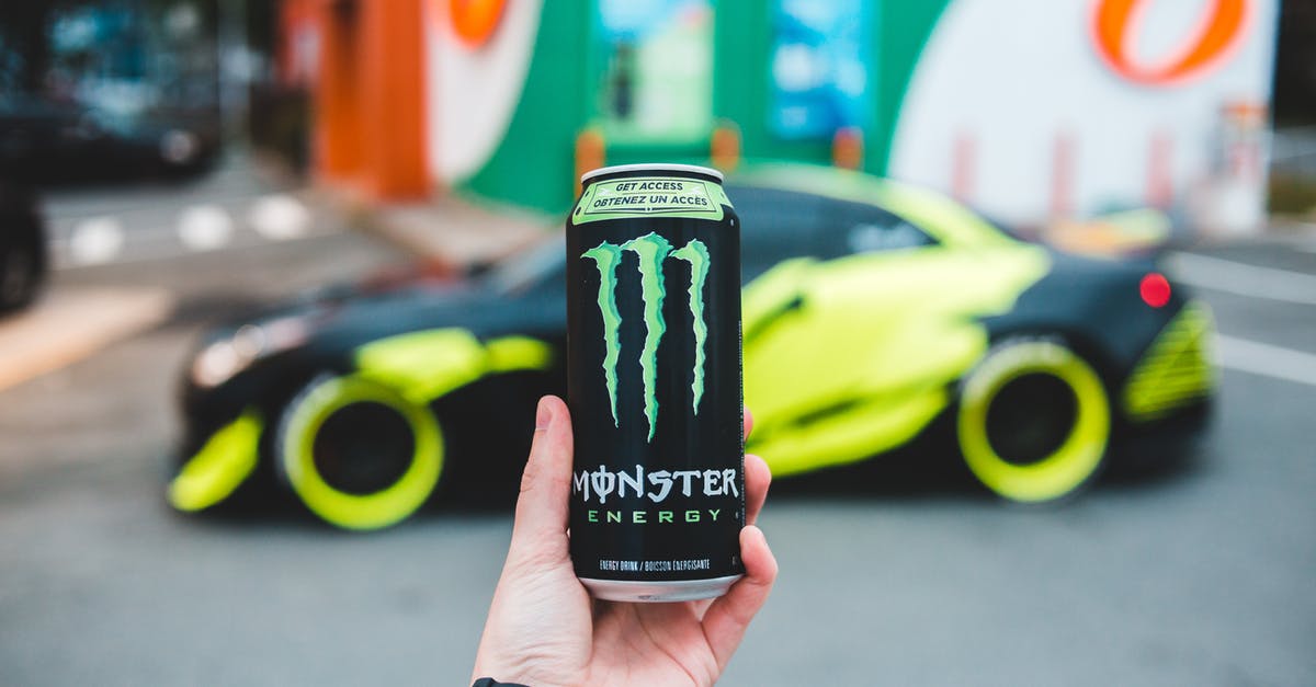 Can you make your own black garlic? - Unrecognizable person holding can of power drink while standing on parking lot near sport car