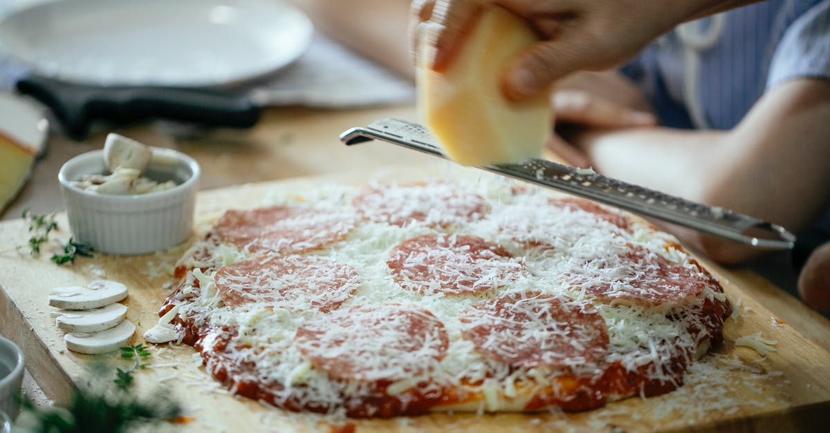 Can you put whole eggs in a blender? - Unrecognizable person grating cheese on pizza