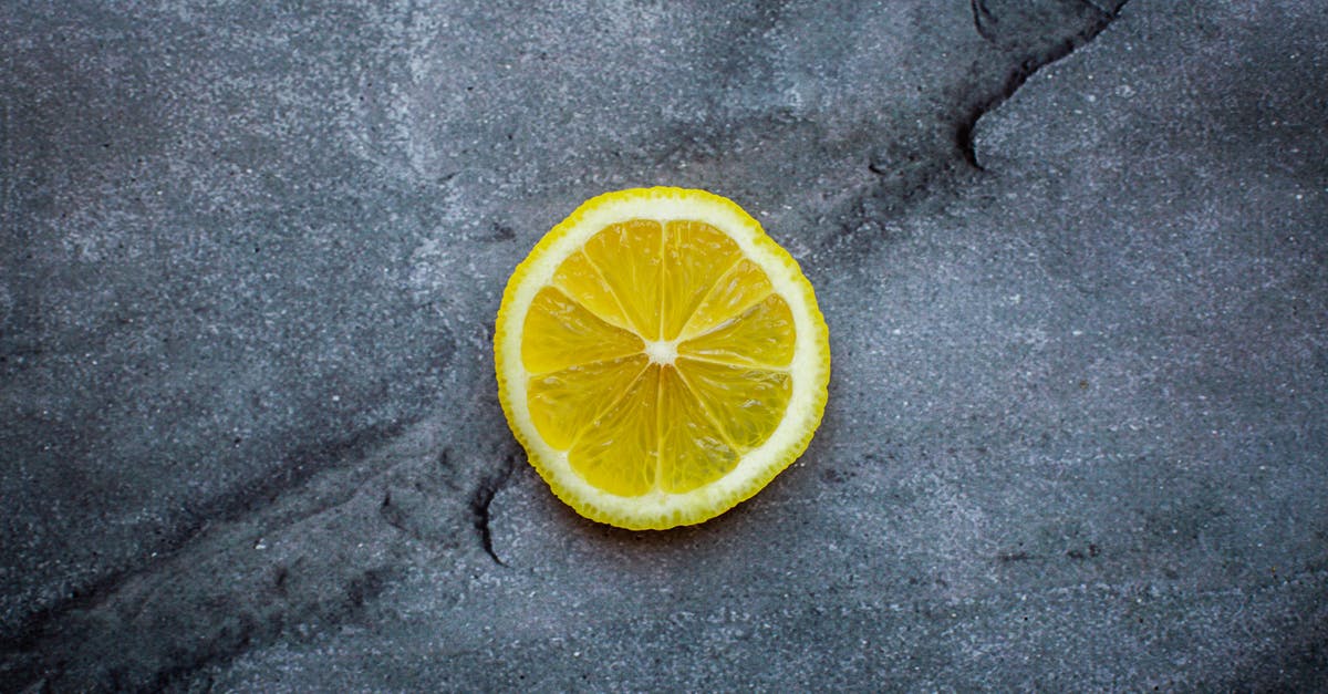 Canned Peppers: Very subtle acidic taste - Top view ripe sour lemon slice placed on dark gray cracked background in studio Canned Peppers: Very subtle acidic taste - Top view ripe sour lemon slice placed on dark gray cracked background in studio