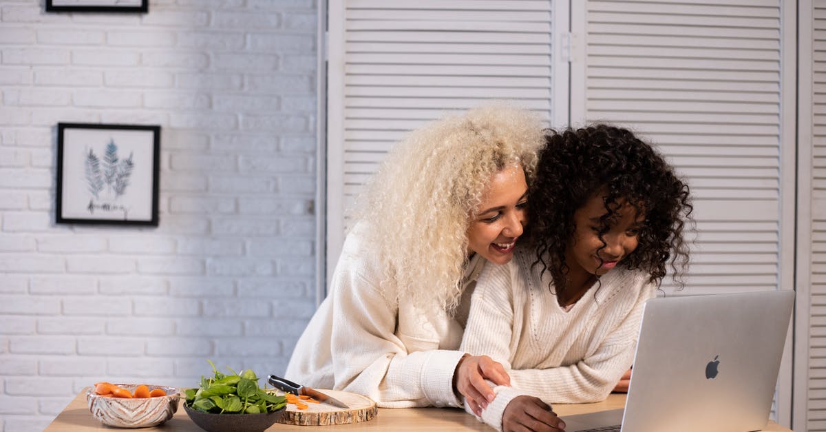 Carrot soup and avoiding the use of a blender? - Smiling black mother and daughter browsing laptop at kitchen counter Carrot soup and avoiding the use of a blender? - Smiling black mother and daughter browsing laptop at kitchen counter