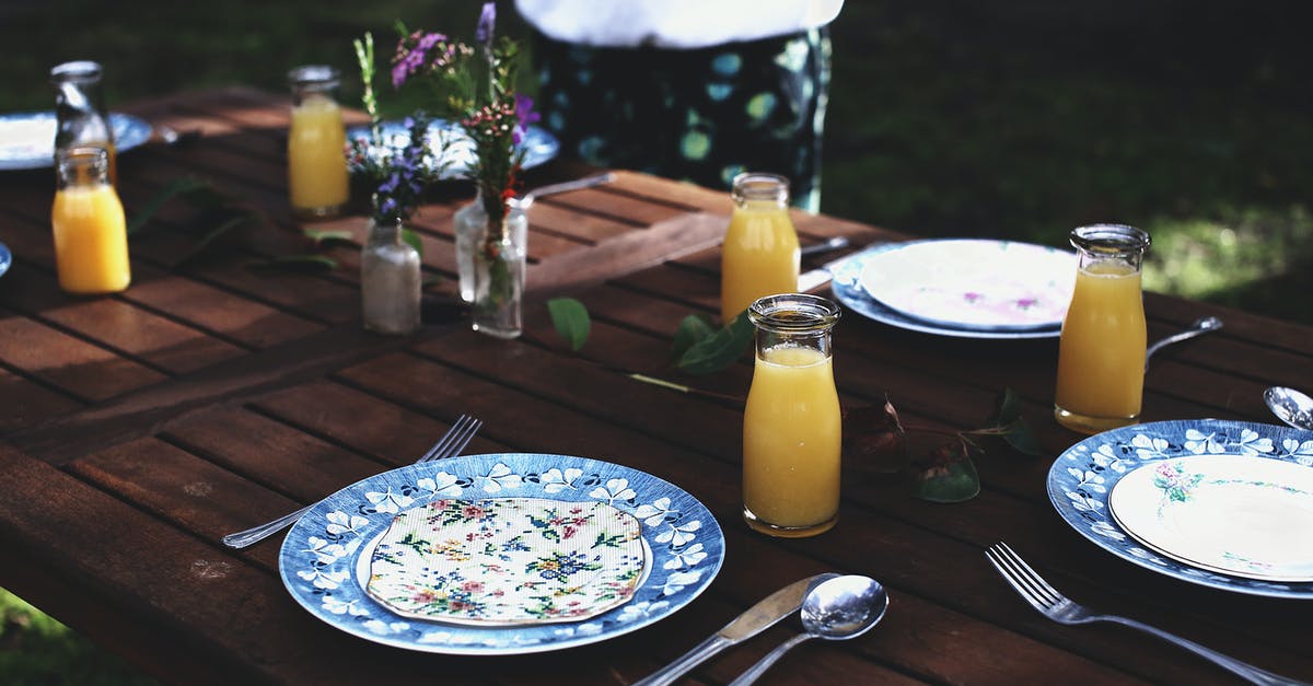 Catering event for BBQ for 30 people. [duplicate] - High angle of crop anonymous person standing in green lawn near wooden table with served plates and natural juices on sunny day