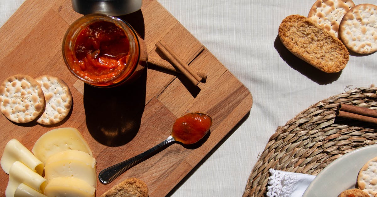 Cellophane lids on jam - Red Sauce in a Glass Jar and on a Spoon on a Wooden Board Cellophane lids on jam - Red Sauce in a Glass Jar and on a Spoon on a Wooden Board