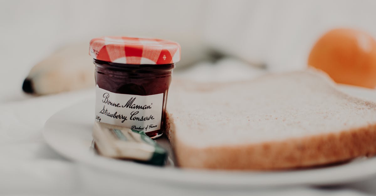 Cellophane lids on jam - Tasty marmalade in glass jar with written title near bread loaf for breakfast on plate Cellophane lids on jam - Tasty marmalade in glass jar with written title near bread loaf for breakfast on plate