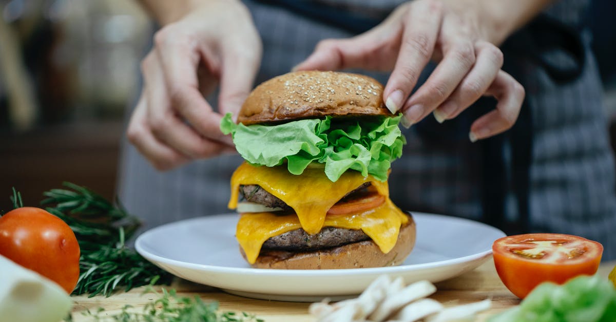 Cheese suggestions to replace melted Velveeta - Faceless female chef preparing delicious double cheeseburger with bread buns and meat patties between fresh vegetables and herbs at home Cheese suggestions to replace melted Velveeta - Faceless female chef preparing delicious double cheeseburger with bread buns and meat patties between fresh vegetables and herbs at home