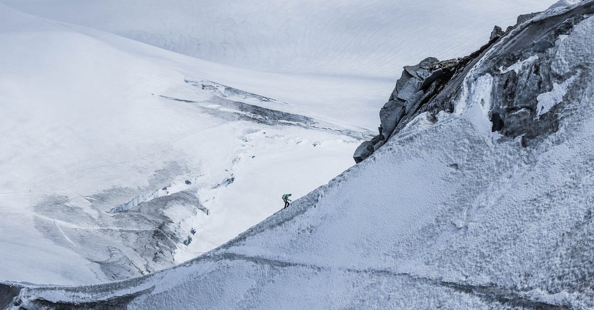 Chiffon gets stiff overnight - From above distant alpinist on snowy rough mountain slope against frozen spacious mountainous valley in daylight Chiffon gets stiff overnight - From above distant alpinist on snowy rough mountain slope against frozen spacious mountainous valley in daylight