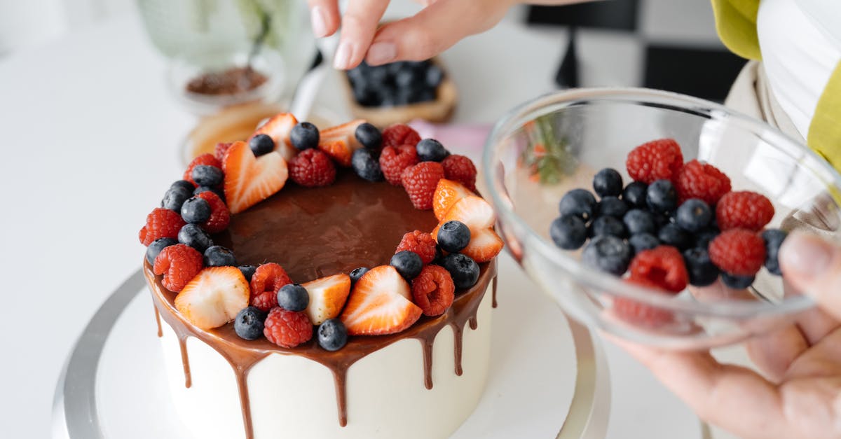 Chocolate Berry Cake with Berries as main batter ingredient? - Female confectioner decorating homemade cake with berries Chocolate Berry Cake with Berries as main batter ingredient? - Female confectioner decorating homemade cake with berries