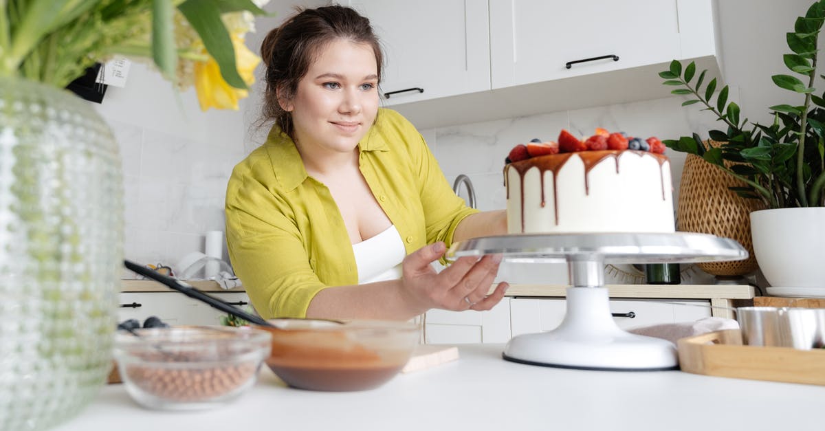 Chocolate Berry Cake with Berries as main batter ingredient? - Smiling young female confectioner in casual clothes finishing decoration of tasty cake with chocolate glaze and berries Chocolate Berry Cake with Berries as main batter ingredient? - Smiling young female confectioner in casual clothes finishing decoration of tasty cake with chocolate glaze and berries