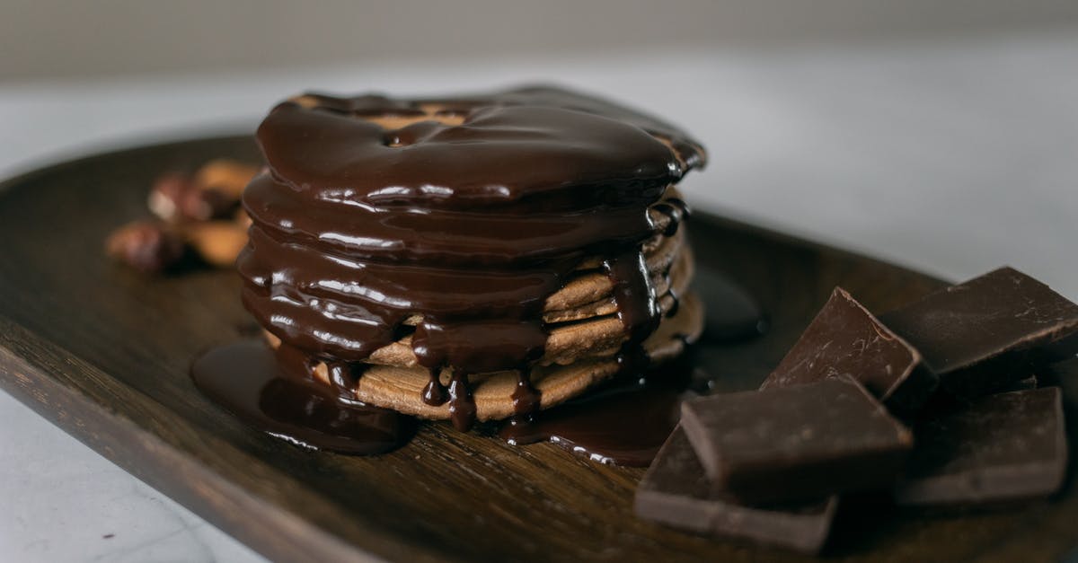 Chocolate for topping didn't melt - Delicious sweet pancakes and melted chocolate on top on wooden board with bar pieces on white table Chocolate for topping didn't melt - Delicious sweet pancakes and melted chocolate on top on wooden board with bar pieces on white table