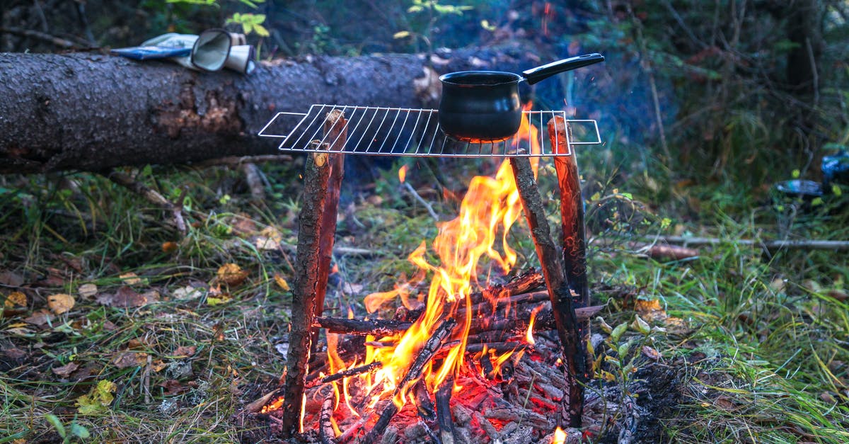 choosing a saucepan material for creams and caramels - Bonfire and rack with saucepan in woods choosing a saucepan material for creams and caramels - Bonfire and rack with saucepan in woods