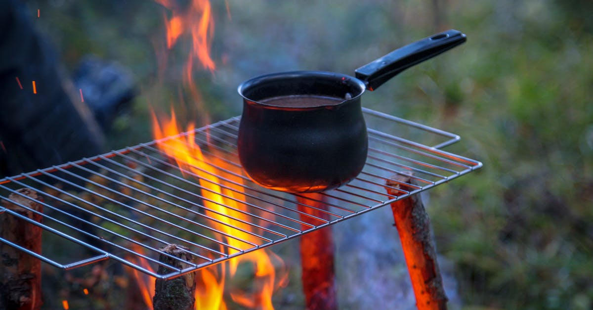 choosing a saucepan material for creams and caramels - Metal saucepan with beverage on metal rack above blazing bonfire in woods in daytime choosing a saucepan material for creams and caramels - Metal saucepan with beverage on metal rack above blazing bonfire in woods in daytime