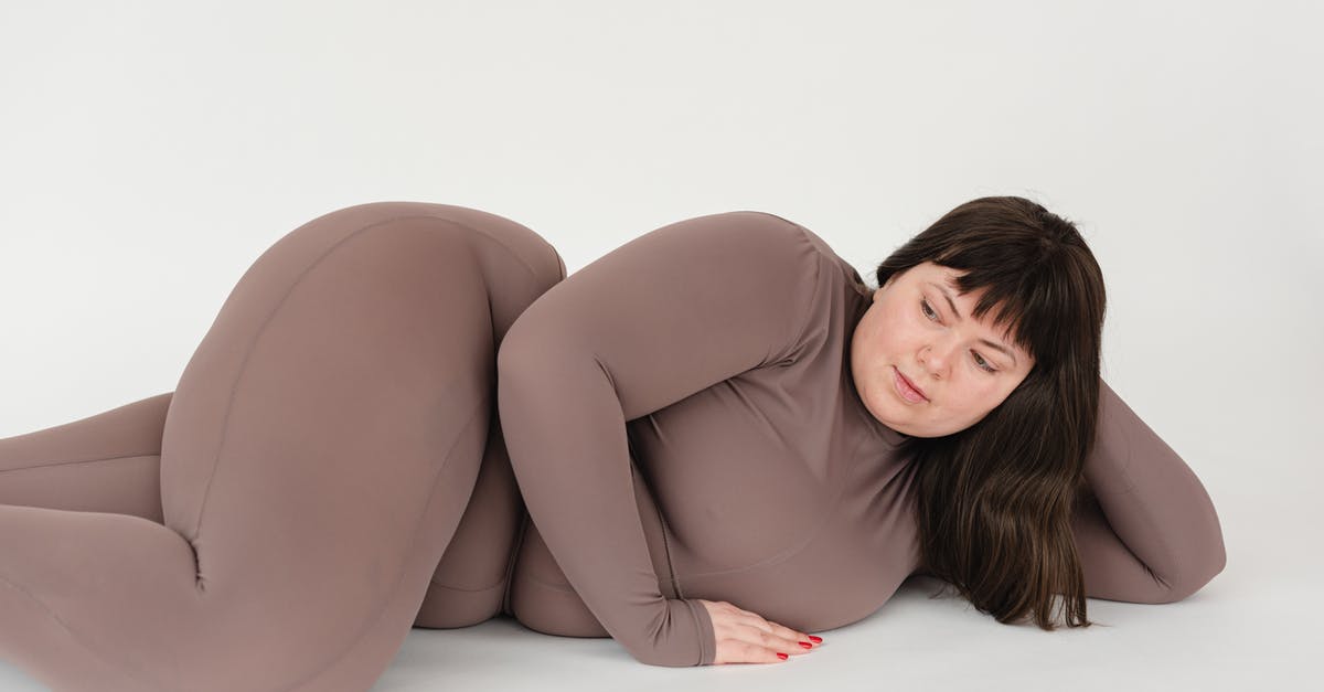 Chunky Peanut Butter - High angle of serious plus size female with long hair leaning on hand while lying against white background Chunky Peanut Butter - High angle of serious plus size female with long hair leaning on hand while lying against white background
