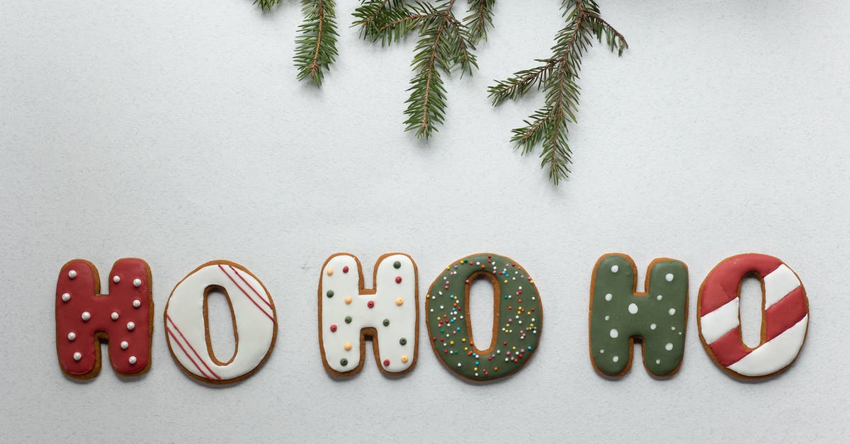 Cinnamon is discoloring my icing - From above of traditional Christmas gingerbread with Ho Ho Ho letters composed with coniferous branch on white background Cinnamon is discoloring my icing - From above of traditional Christmas gingerbread with Ho Ho Ho letters composed with coniferous branch on white background