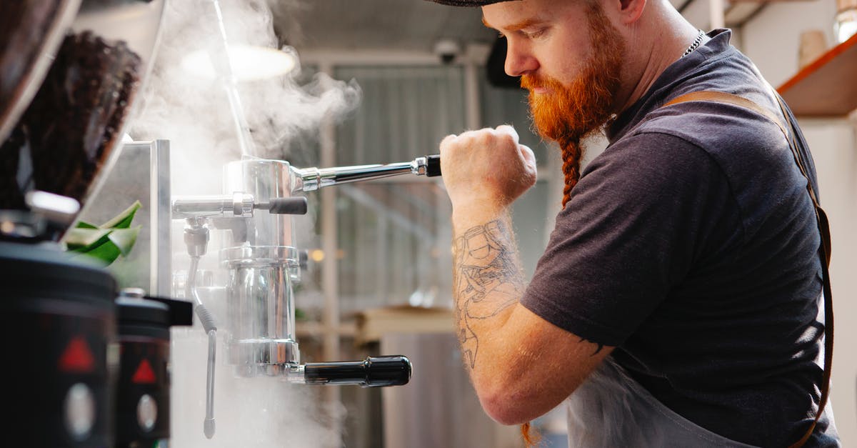 Cleaning burr coffee grinder - Crop employee cleaning espresso maker with vapor at work Cleaning burr coffee grinder - Crop employee cleaning espresso maker with vapor at work