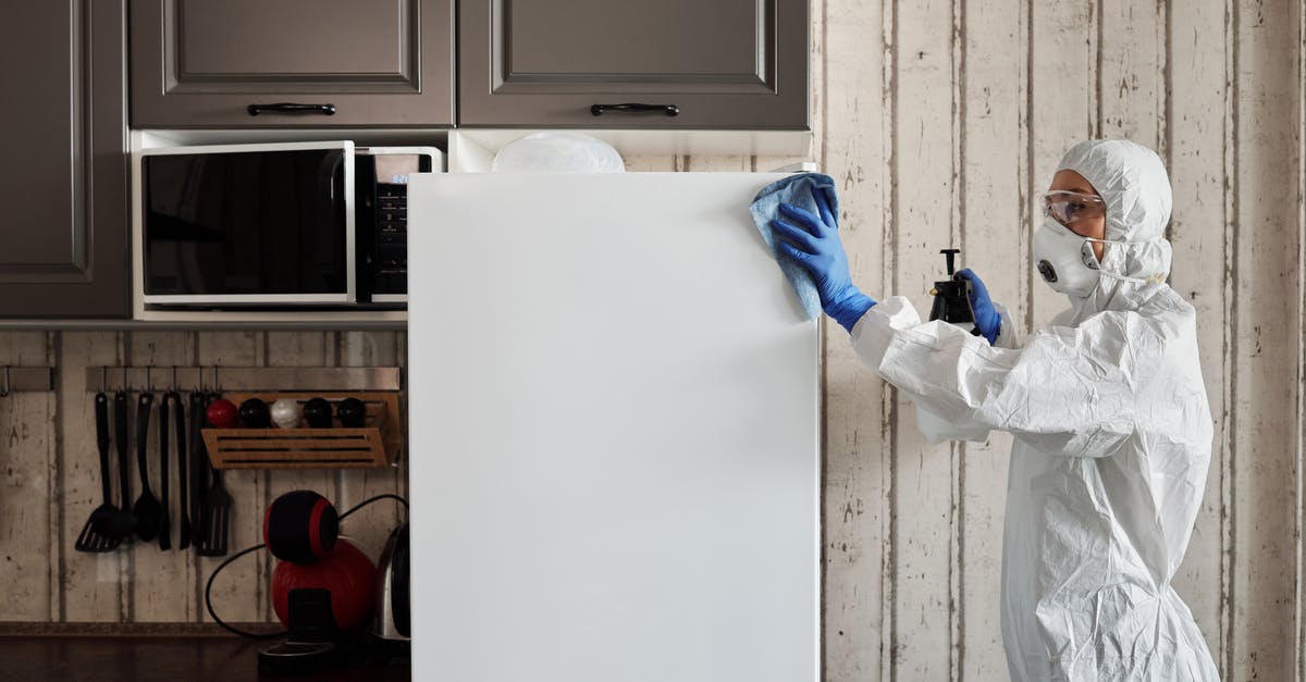 Cleaning tin discoloration on copper/tin lid - Person in Protective Suit Disinfecting A Refrigerator Cleaning tin discoloration on copper/tin lid - Person in Protective Suit Disinfecting A Refrigerator