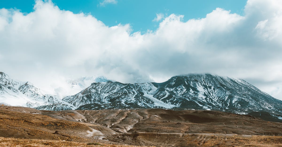 Clear soup with snow globe flakes - Scenic snowy mountains with peaks hiding in fluffy clouds Clear soup with snow globe flakes - Scenic snowy mountains with peaks hiding in fluffy clouds