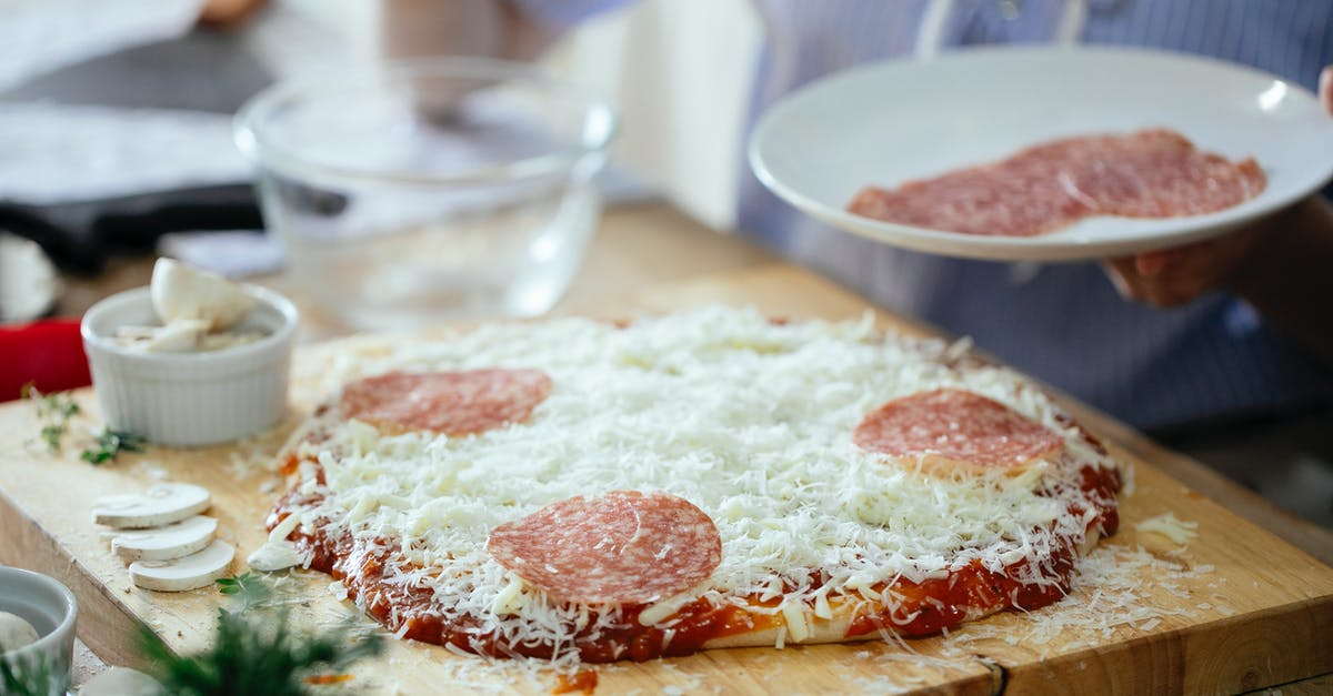Coating meat in flour before browning, bad idea? - Crop anonymous person standing near table with uncooked homemade pizza and adding slices of salami while preparing in kitchen at daytime Coating meat in flour before browning, bad idea? - Crop anonymous person standing near table with uncooked homemade pizza and adding slices of salami while preparing in kitchen at daytime