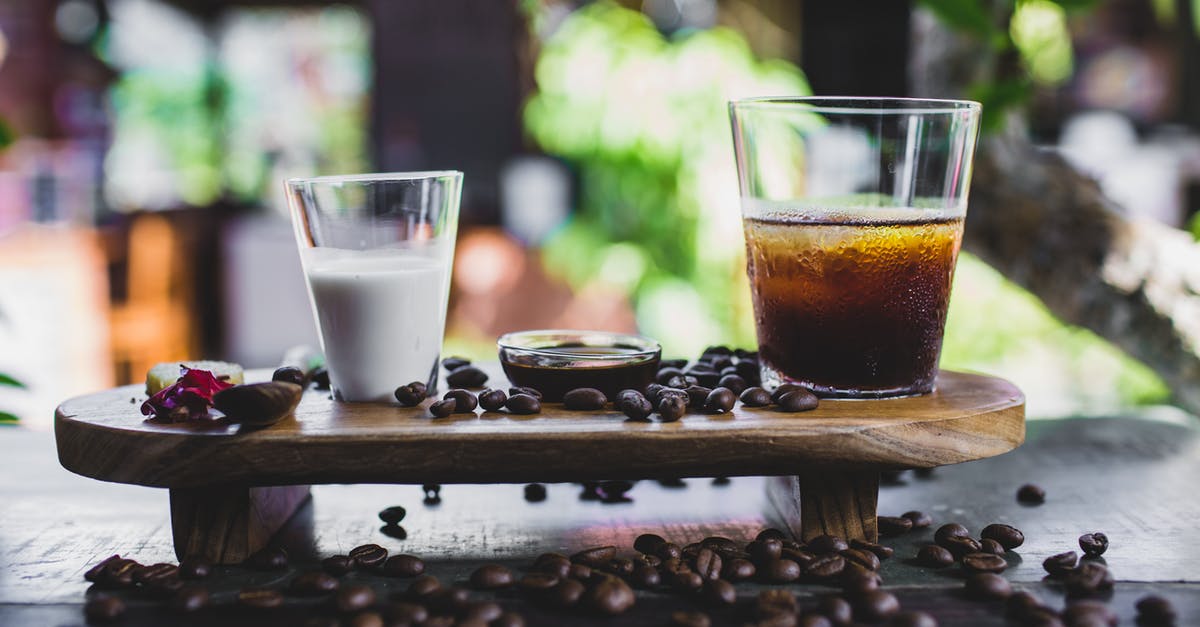 Coconut milk in iced coffee - Glass of cold coffee served with milk and beans Coconut milk in iced coffee - Glass of cold coffee served with milk and beans