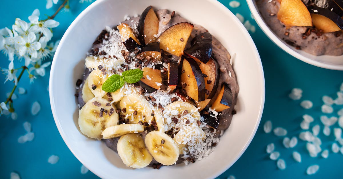 Coconut yoghurt too thick - Top view of appetizing smoothie bowl topped with fresh sliced bananas and plums and decorated with coconut flakes Coconut yoghurt too thick - Top view of appetizing smoothie bowl topped with fresh sliced bananas and plums and decorated with coconut flakes