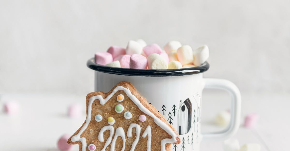 Coffee flavored melted chocolate for drizzling over cookies? - Festive gingerbread cookie with inscription 2021 placed against mug of delicious hot drink garnished with sweet marshmallows and served on white table Coffee flavored melted chocolate for drizzling over cookies? - Festive gingerbread cookie with inscription 2021 placed against mug of delicious hot drink garnished with sweet marshmallows and served on white table