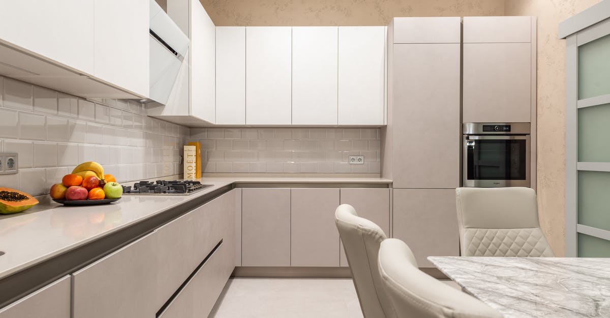 Condensation inside packed, refrigerated food - Table with chairs placed near cupboards and counter with stove and fruits in stylish kitchen with modern kitchenware and door Condensation inside packed, refrigerated food - Table with chairs placed near cupboards and counter with stove and fruits in stylish kitchen with modern kitchenware and door