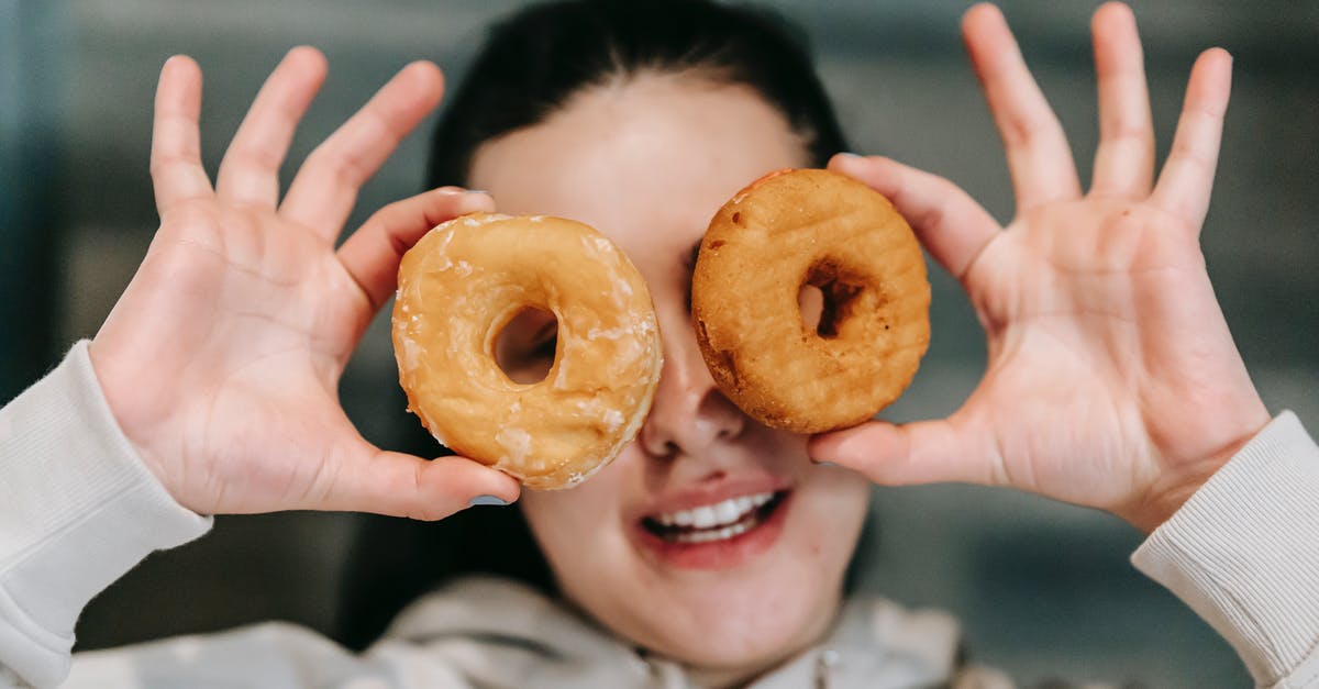Convert weight of Confectioners sugar to caster sugar - Positive young female in casual clothes smiling while covering eyes with delicious doughnuts Convert weight of Confectioners sugar to caster sugar - Positive young female in casual clothes smiling while covering eyes with delicious doughnuts