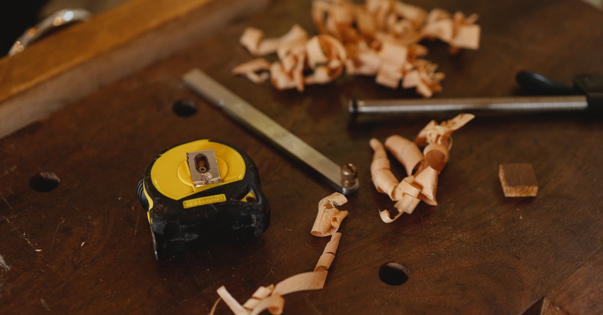converting dried measurements to soaked measurements - From above of tape measure near metal carpentry instruments with wooden shavings in workshop