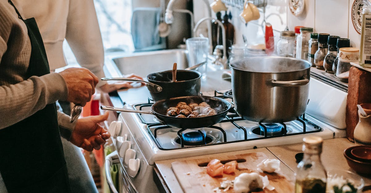 Cook lentils before or after shaping into veggie meatballs? - Anonymous man frying meatballs standing in kitchen with wife Cook lentils before or after shaping into veggie meatballs? - Anonymous man frying meatballs standing in kitchen with wife