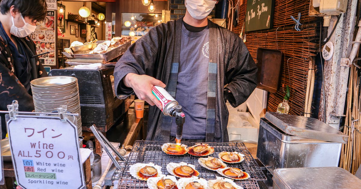 Cook Time vs. Cook Temp trade off - Asian man in mask frying clams on street market Cook Time vs. Cook Temp trade off - Asian man in mask frying clams on street market