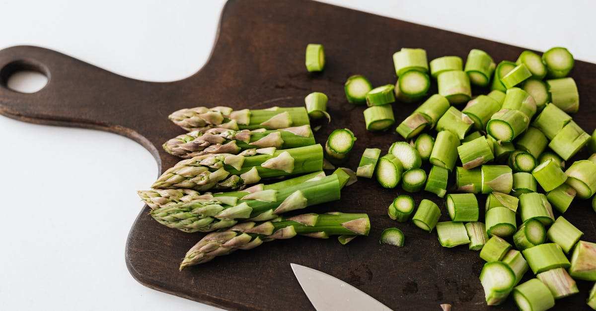 Cooked white asparagus is stringy - Bunch of asparagus and knife on cutting board Cooked white asparagus is stringy - Bunch of asparagus and knife on cutting board