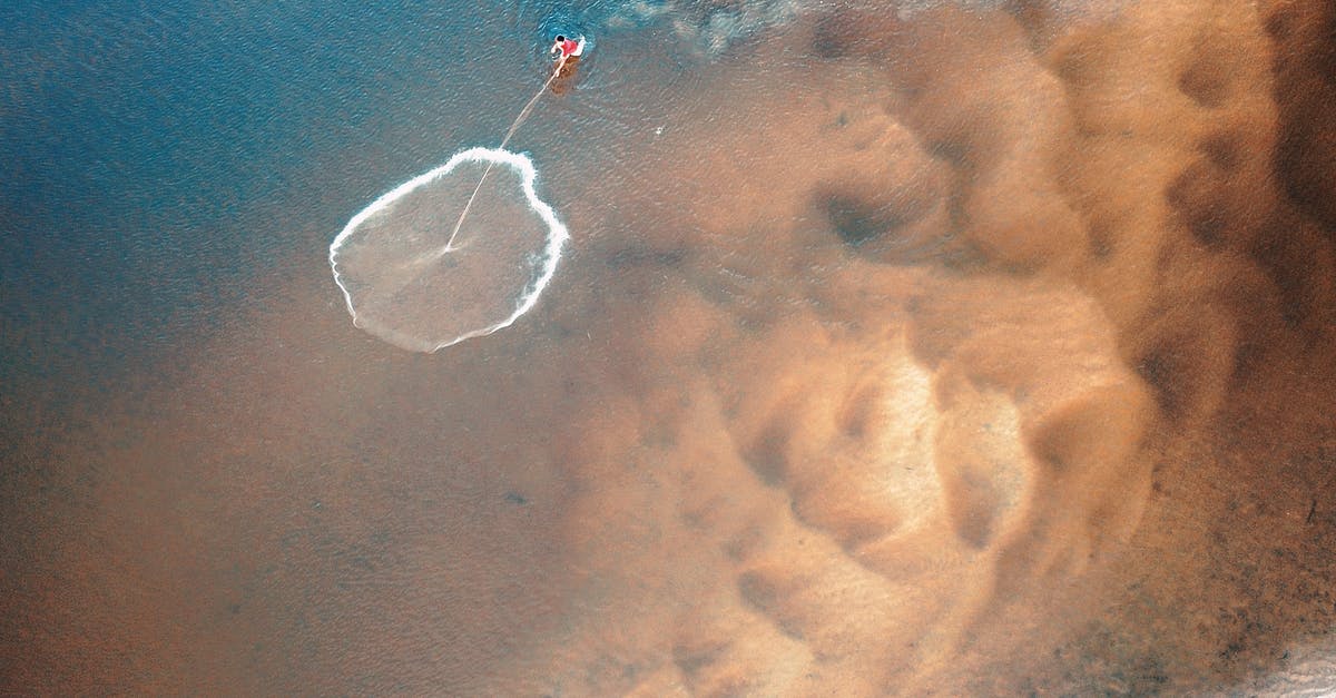Cookies end up with a wavy bottom - From above of anonymous person throwing fishing net from pure rippled sea with sandy bottom Cookies end up with a wavy bottom - From above of anonymous person throwing fishing net from pure rippled sea with sandy bottom