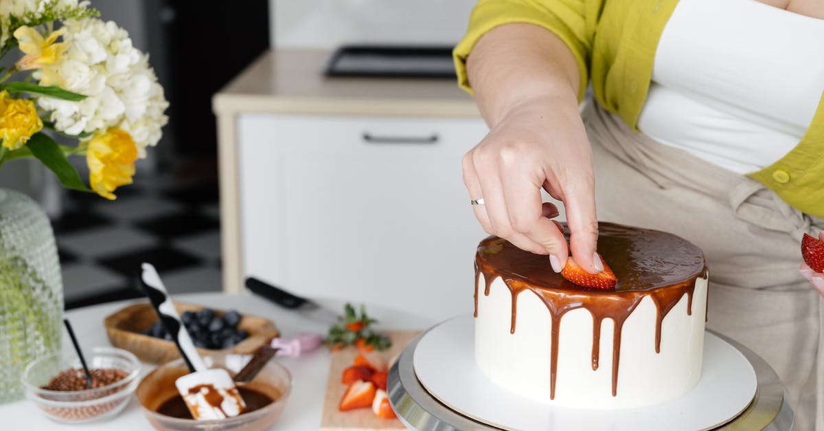 Cooking oranges to put in a cake - Crop anonymous female confectioner putting slices on strawberry on cake with chocolate frosting Cooking oranges to put in a cake - Crop anonymous female confectioner putting slices on strawberry on cake with chocolate frosting