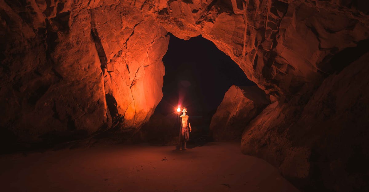 Crème brûlée without torch - Person Standing and Holding Lamp Inside Cave Crème brûlée without torch - Person Standing and Holding Lamp Inside Cave
