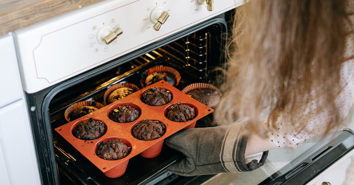 Crumble added to muffins before baking - A Person Holding a Baking Tray Crumble added to muffins before baking - A Person Holding a Baking Tray