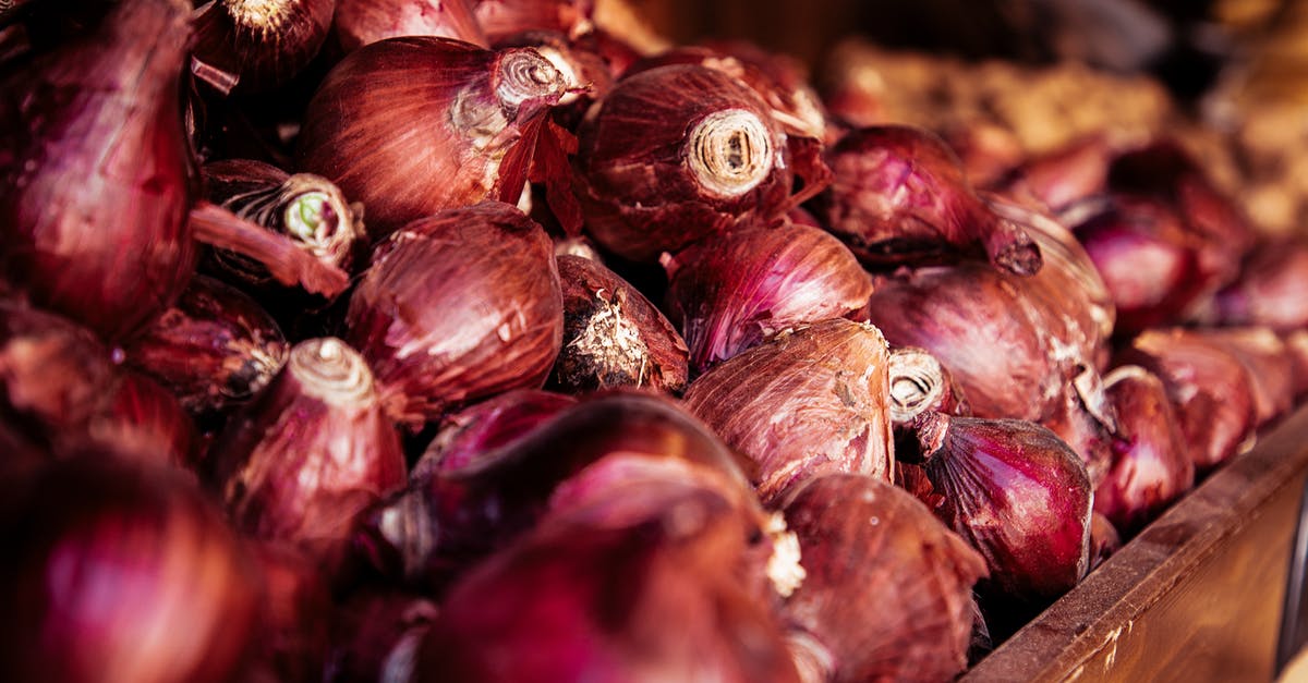 Crunchy onions in soup? - From above of wooden box with pile of bright raw onions with dry red husk in local bazaar Crunchy onions in soup? - From above of wooden box with pile of bright raw onions with dry red husk in local bazaar