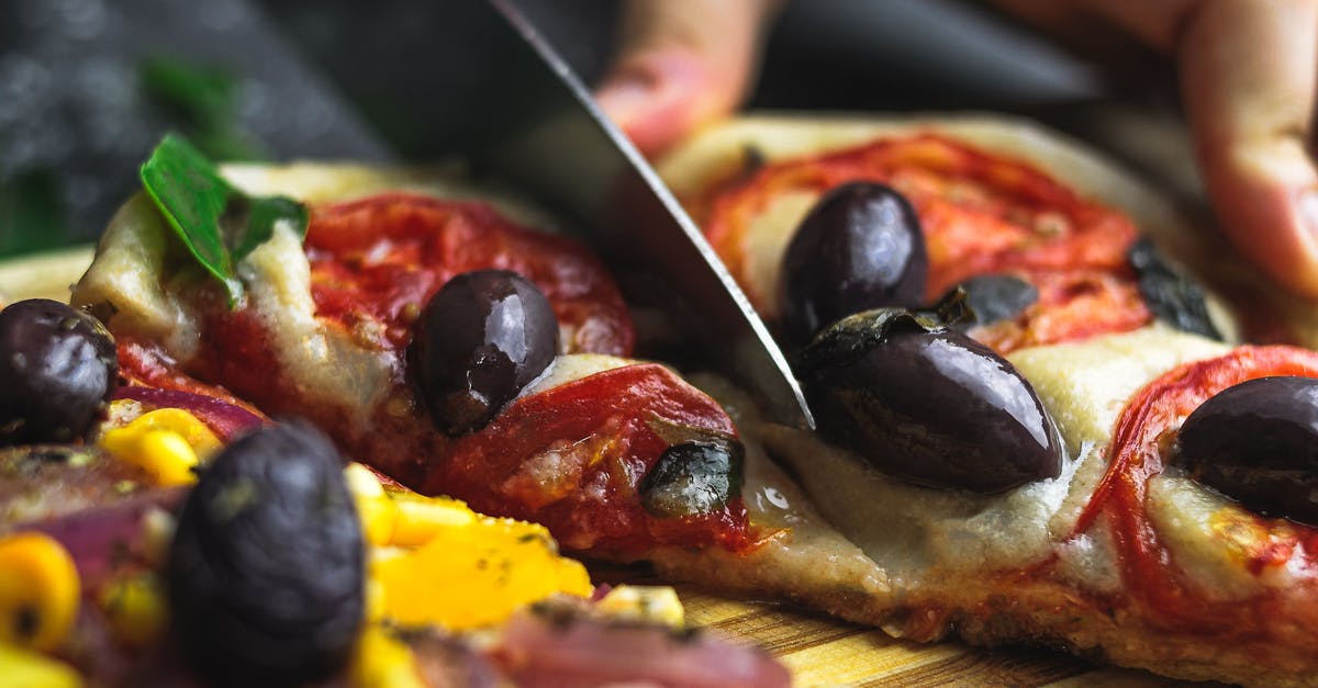 Cut food with fork and sharp knife - metal in food? - Crop anonymous person cutting tasty pizza with cheese tomato and olive on wooden board Cut food with fork and sharp knife - metal in food? - Crop anonymous person cutting tasty pizza with cheese tomato and olive on wooden board