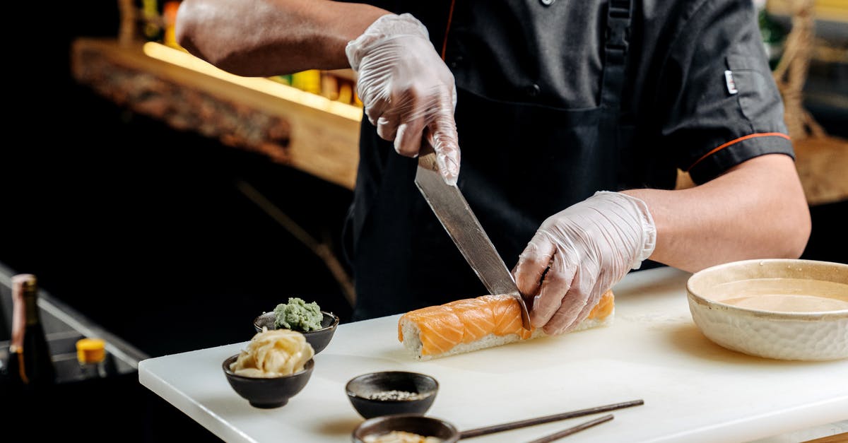 Cutting Sushi Rolls - Person Slicing Meat on Chopping Board