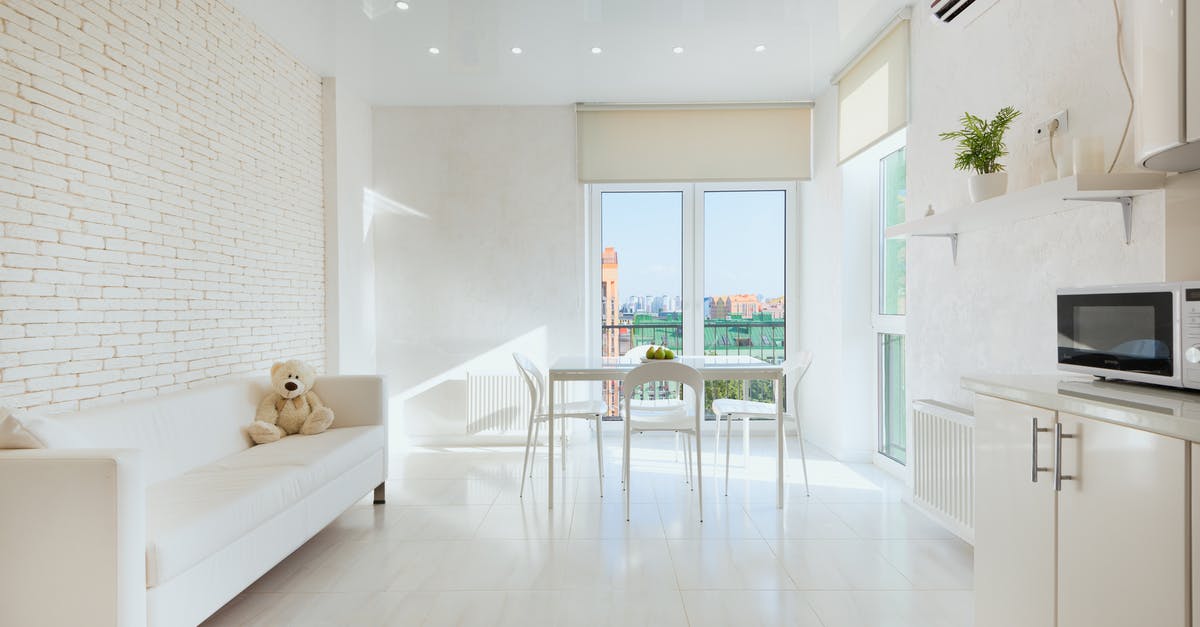 damaged microwave door - Interior of light kitchen with plush toy on sofa near dining table placed closet to panoramic balcony doors damaged microwave door - Interior of light kitchen with plush toy on sofa near dining table placed closet to panoramic balcony doors