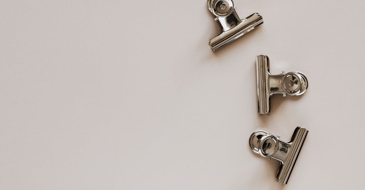 Dark grey residue from newly purchased stainless steel kitchen items? - From above of identical metallic clips made of solid material with smooth surface on beige background Dark grey residue from newly purchased stainless steel kitchen items? - From above of identical metallic clips made of solid material with smooth surface on beige background