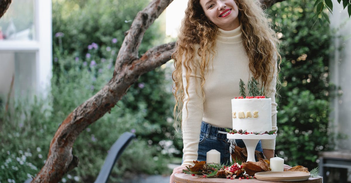 Decoration food long-term preservation - Young female with long hair in casual clothes with fresh appetizing cake on small round table in backyard Decoration food long-term preservation - Young female with long hair in casual clothes with fresh appetizing cake on small round table in backyard