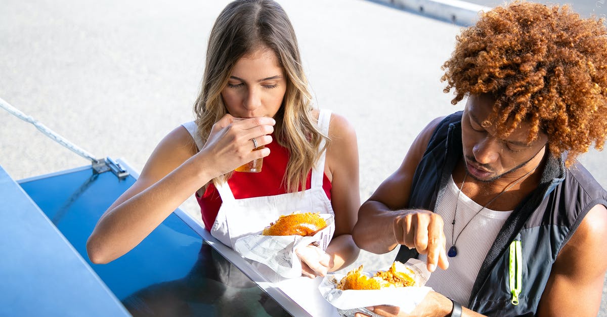 Deep frying - beer batter vs. bread crumbs - High angle of diverse couple eating unhealthy food made of buns and fried meat at counter Deep frying - beer batter vs. bread crumbs - High angle of diverse couple eating unhealthy food made of buns and fried meat at counter