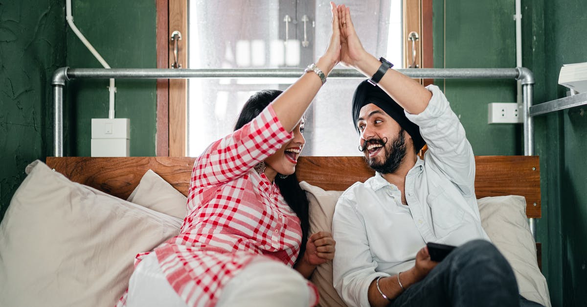 Deep frying without schnitzels sticking to each other - Positive adult ethnic couple in casual clothes giving high five to each other while resting on bed in small bedroom with sticking out pipe Deep frying without schnitzels sticking to each other - Positive adult ethnic couple in casual clothes giving high five to each other while resting on bed in small bedroom with sticking out pipe