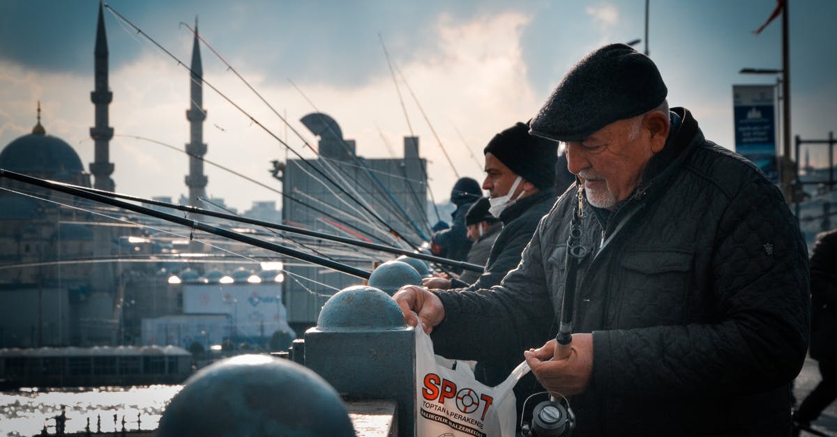 Defrosting Fish without Bag - Men Fishing on Bridge in City with Mosque in Background Defrosting Fish without Bag - Men Fishing on Bridge in City with Mosque in Background