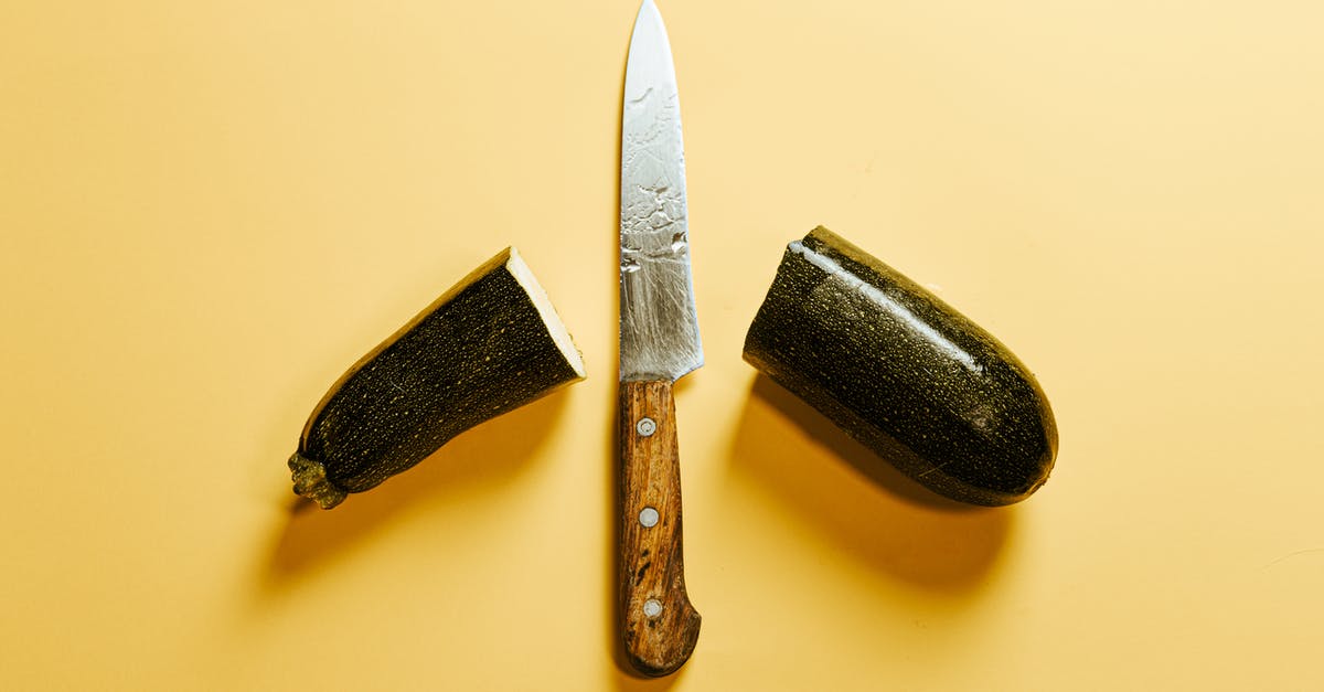 Difference between natural and organic - From above of fresh sliced zucchini placed on yellow background with sharp knife with wooden handle between halves of vegetable Difference between natural and organic - From above of fresh sliced zucchini placed on yellow background with sharp knife with wooden handle between halves of vegetable