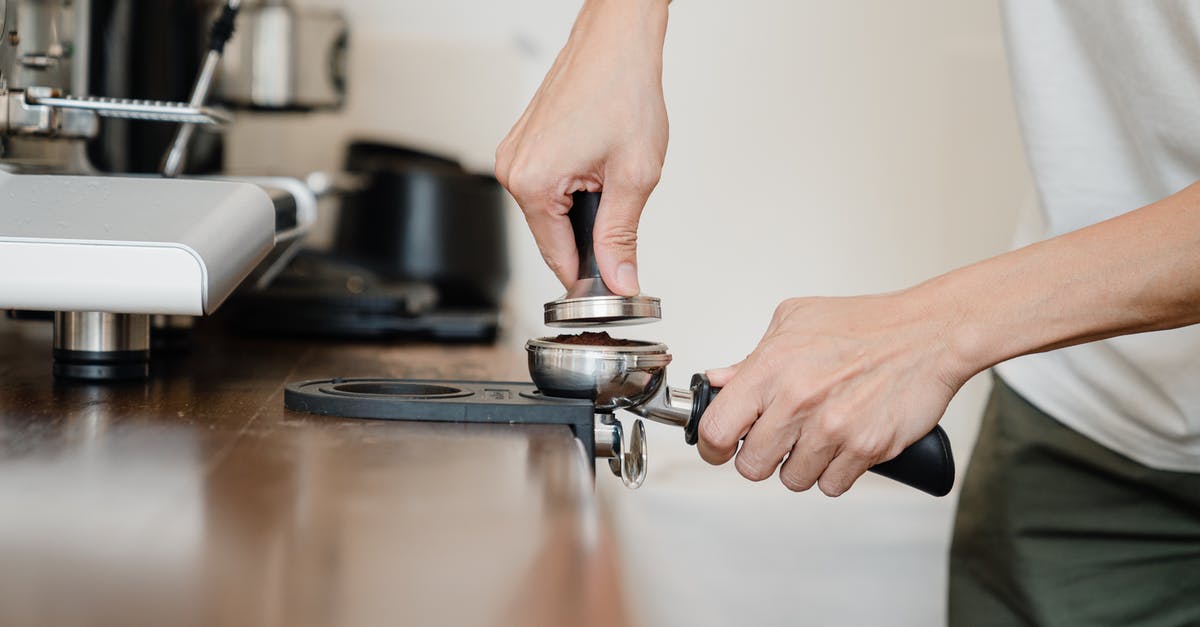 Differences between coffee made with french press or espresso machine? - Crop anonymous male barista in casual clothes pressing ground coffee into metal portafilter by using tamper while working in contemporary kitchen Differences between coffee made with french press or espresso machine? - Crop anonymous male barista in casual clothes pressing ground coffee into metal portafilter by using tamper while working in contemporary kitchen