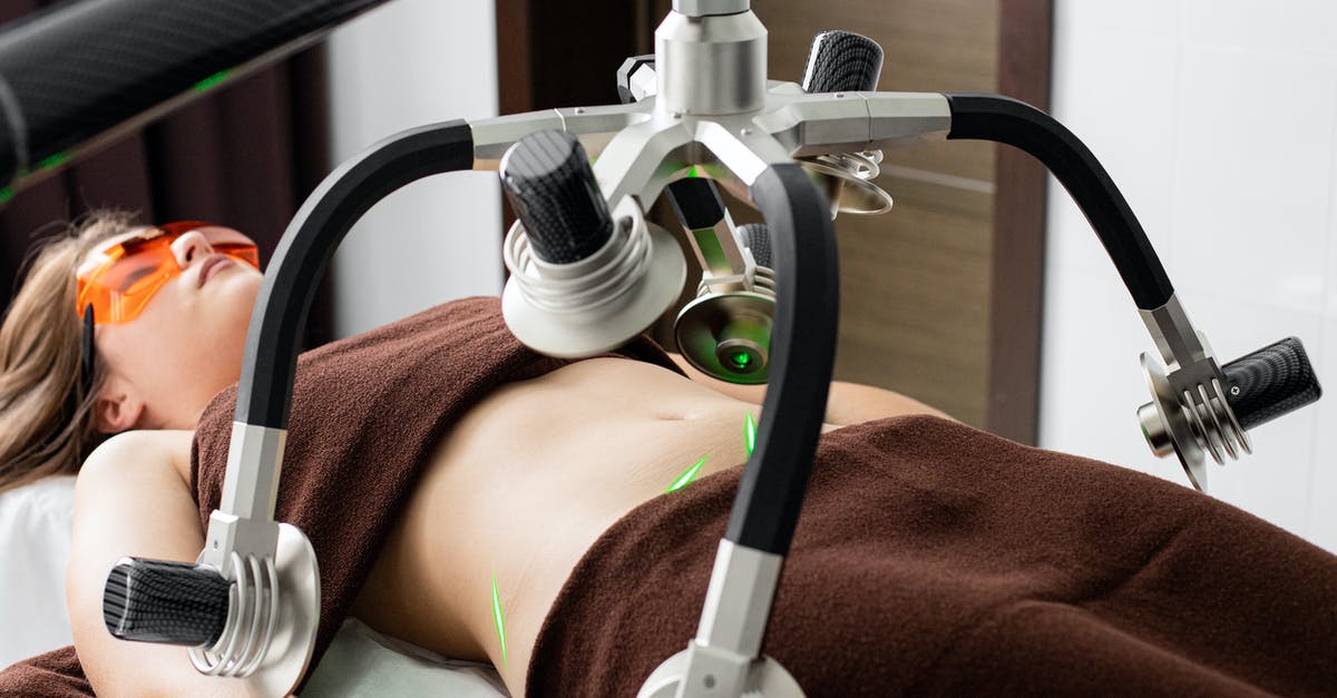 Discarding ox heart fat - Female client lying on table under lasers of modern weight loss machine on belly during liposuction procedure in medical clinic Discarding ox heart fat - Female client lying on table under lasers of modern weight loss machine on belly during liposuction procedure in medical clinic