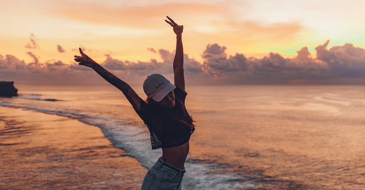 Dishwasher with side brackets for on top shelf: what are they for? - Side view fit lady in casual shorts and cap enjoying evening on seashore while standing with arms raised against calm endless sea and majestic bright cloudy orange sky during sunset