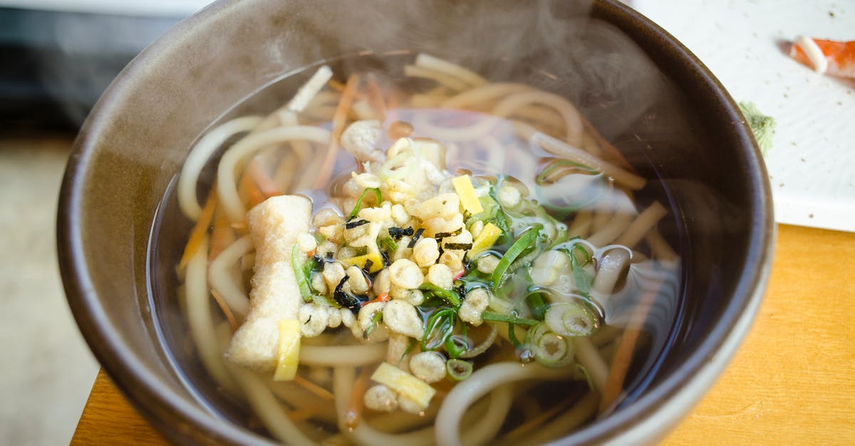 Dispensing fair shares of inhomogeneous soup - Noodle Soup With Sliced Vegetables in Black Ceramic Bowl Dispensing fair shares of inhomogeneous soup - Noodle Soup With Sliced Vegetables in Black Ceramic Bowl